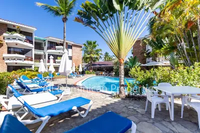 a resort with a pool and chairs and palm trees at Club Residential, Sosua in Sosúa