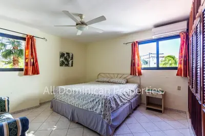 a bedroom with a bed and two windows at Club Residential, Sosua in Sosúa