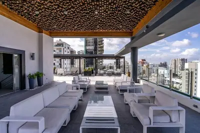 a rooftop patio with white furniture and a view of the city at Dream Rooftop Downtown View in Santo Domingo