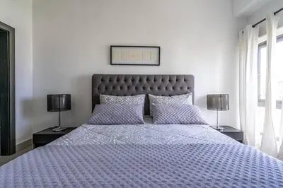 a bedroom with a bed with a blue comforter and two lamps at Dream Rooftop Downtown View in Santo Domingo