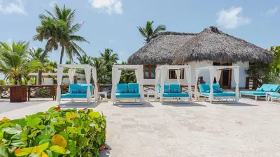 a resort with blue chairs and a thatch roof at 1BDR Rockstar's Paradise in front of Hard Rock H. in Punta Cana