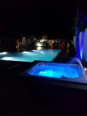a large swimming pool at night with a blue tub at La casita del sol in Las Terrenas