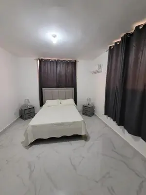 a white bedroom with a bed and two night stands at Close in Santo Domingo