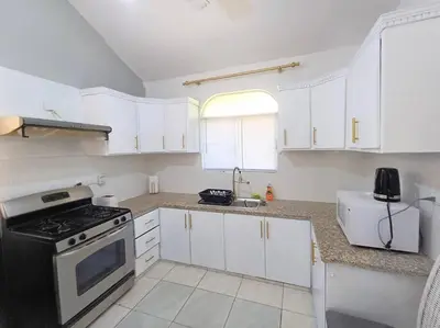 a kitchen with white cabinets and a stove at Linkzup Playa Laguna Villa in Sosúa