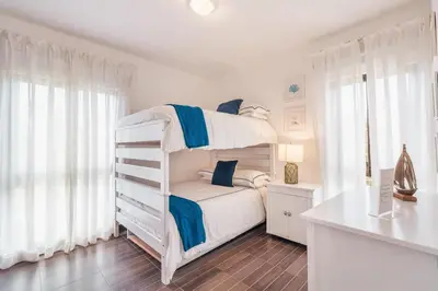 a white bedroom with a bunk bed with blue accents at Unique gem penthouse in playa bonita in Las Terrenas