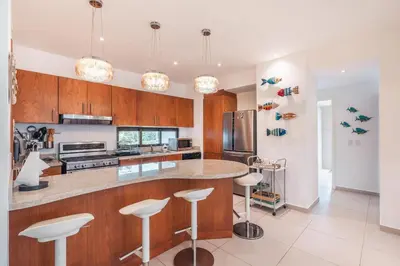 a kitchen with wooden cabinets and a counter with stools at Unique gem penthouse in playa bonita in Las Terrenas