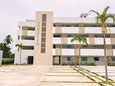 a building with palm trees in front of it at Exclusivo penthouse con piscina en Playa Bávaro in Punta Cana