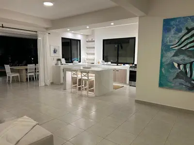 a living room with a table and a kitchen at Villa Antonia Spectacular Private Stay with Pool, Just Steps from the Beach, Housekeeping & Kitchen in Exclusive Gated Community in Las Terrenas
