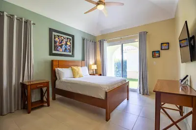 a bedroom with a bed and a desk and a window at Sosua Ocean Village, Villa 11, Garden Dream in Sosúa