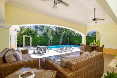 a living room with wicker furniture and a swimming pool at Sosua Ocean Village, Villa 11, Garden Dream in Sosúa