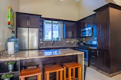 a kitchen with wooden cabinets and a island with bar stools at Sosua Ocean Village, Villa 11, Garden Dream in Sosúa