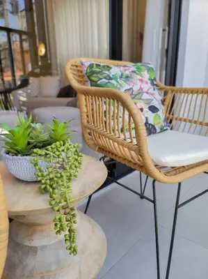 a wicker chair with a pillow and a plant on a table at Luxury Apartment Downtown in Santiago de los Caballeros