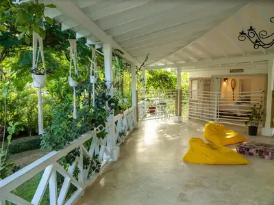a porch with yellow cushions and plants on it at JandalaVillage in Las Terrenas