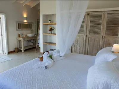 a stuffed animal is sitting on a white bed at JandalaVillage in Las Terrenas