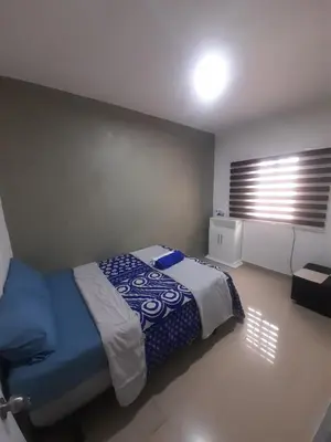 a bedroom with a bed with a blue blanket and a window at Cerca del divino niño I WiFi I TV in Constanza