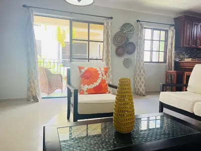 a living room with a chair and a glass table at Cozy 2 bed apartment garden views close to Playa Bavaro in Punta Cana