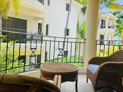 a patio with chairs and a table and a balcony at Cozy 2 bed apartment garden views close to Playa Bavaro in Punta Cana
