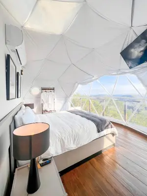 a bedroom in a tent with a bed and a table at The Domes Jarabacoa in Jarabacoa