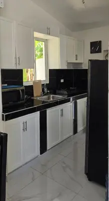a kitchen with white cabinets and a black refrigerator at Villa el real los patos in Los Patos