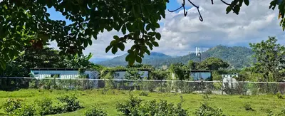 a house in a field with mountains in the background at BlueEcolandia bungalows AIRE in Jarabacoa