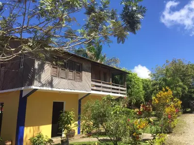 a yellow house with a balcony and some trees at Los Bohios Campo Añil in Jarabacoa