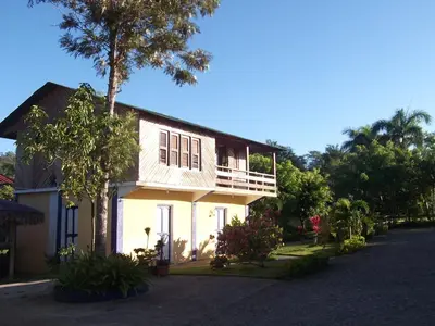 a white house with a balcony and a tree at Los Bohios Campo Añil in Jarabacoa