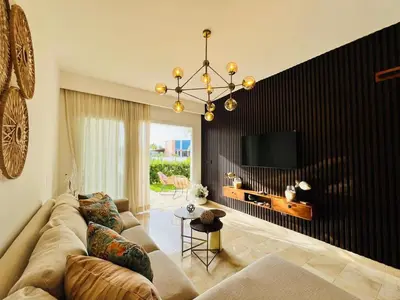 a living room with a couch and a tv at Paradise Pool Front and Beach Condo at Punta Cana in Punta Cana
