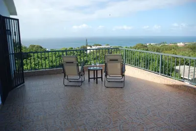 a balcony with three chairs and a table and the ocean at E&J Boutique Residences in Sosúa