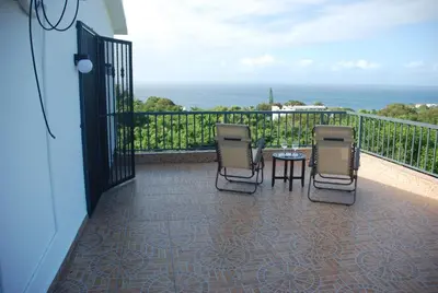 a balcony with three chairs and a table with a view at E&J Boutique Residences in Sosúa