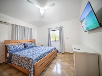 a bedroom with a bed and a tv on the wall at Villa Selena - 5br Villa In Sosua Center in Sosúa