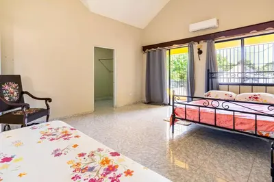 a bedroom with two beds and a chair at Casa para vacacionar - El patio de Olivia in San Felipe de Puerto Plata