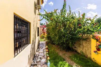 a stone walkway next to a building with flowers at Casa para vacacionar - El patio de Olivia in San Felipe de Puerto Plata