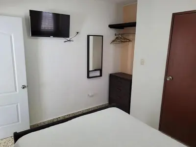 a bedroom with a bed and a television on the wall at Cozy Apartment Studio in Santo Domingo