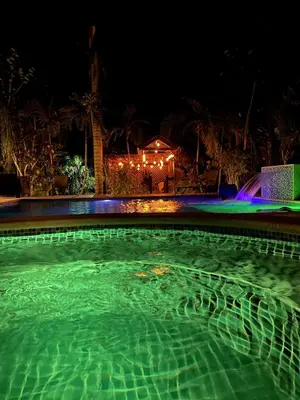 a swimming pool with green water at night at Villa El cocotero in La Joya