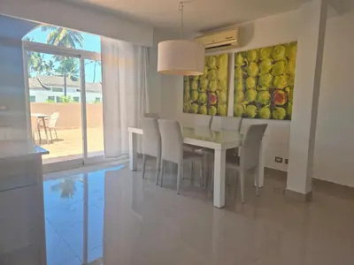 a dining room with a table and chairs and a painting at bello PH cerca de la playa in Punta Cana