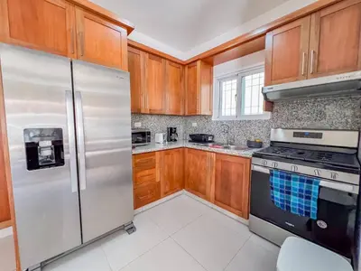 a kitchen with wooden cabinets and stainless steel appliances at New 2BR APT in Sosua town, close to strip and next to supermarket in Sosúa