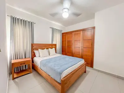 a bedroom with a large bed and a wooden cabinet at New 2BR APT in Sosua town, close to strip and next to supermarket in Sosúa