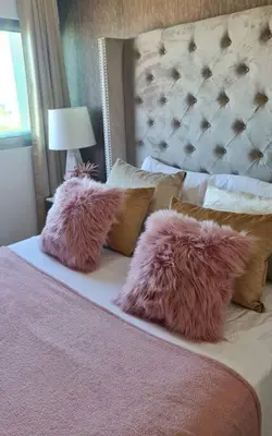 a bed with two pink fluffy pillows on it at Luxury penthouse con jacuzzi privado, Gym, pool in Santo Domingo