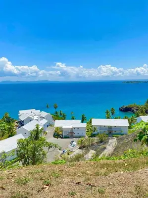 a group of white buildings on a hill next to the ocean at Ocean Front Deluxe Condo in Punta Balandra