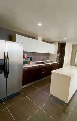 a kitchen with a stainless steel refrigerator and brown cabinets at Ocean Front Deluxe Condo in Punta Balandra