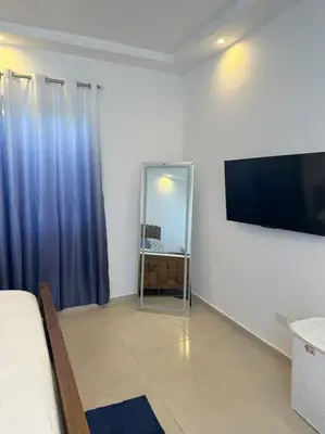 a living room with a television and blue curtains at Timeless Luxury Villa-Ocean View 3BRM-5Bath-Pool in San Felipe de Puerto Plata