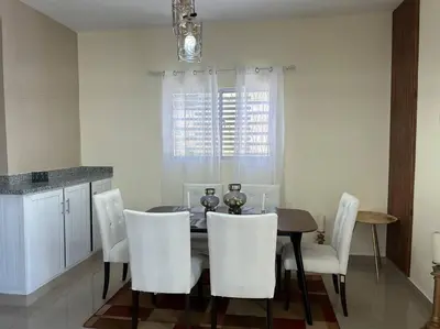 a dining room with a table and white chairs at Apartamento hermoso in Los Macos