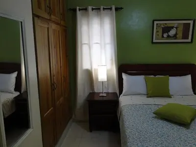 a bedroom with a bed with a green wall at Apartamento Carmil I in Santo Domingo