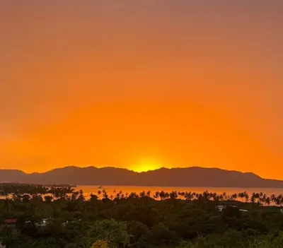 a sunset over the water with mountains in the background at Vistas Galeras in Madama