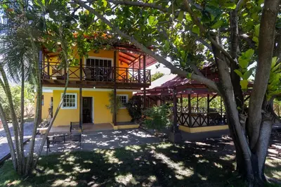 a yellow house with a balcony and trees at Casa Palmar in Palmar Arriba