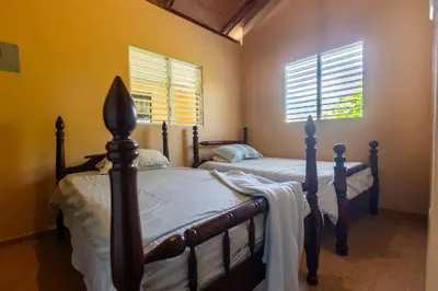 two beds in a bedroom with two windows at Casa Palmar in Palmar Arriba