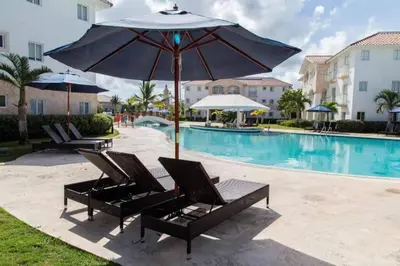 a pair of lounge chairs with an umbrella next to a pool at Cadaques Caribe Bayahibe Private beach in Bayahibe