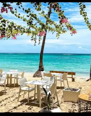 a beach with tables and chairs and the ocean at Beautiful Place in los Corales bavaro in Punta Cana