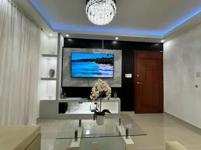 a living room with a television on a wall at Casa las América in La Cana