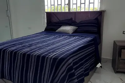 a bedroom with a bed with a blue striped comforter at Bocachica house,apts,village in Jubey